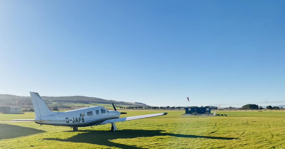 Light aircraft parked on grass.