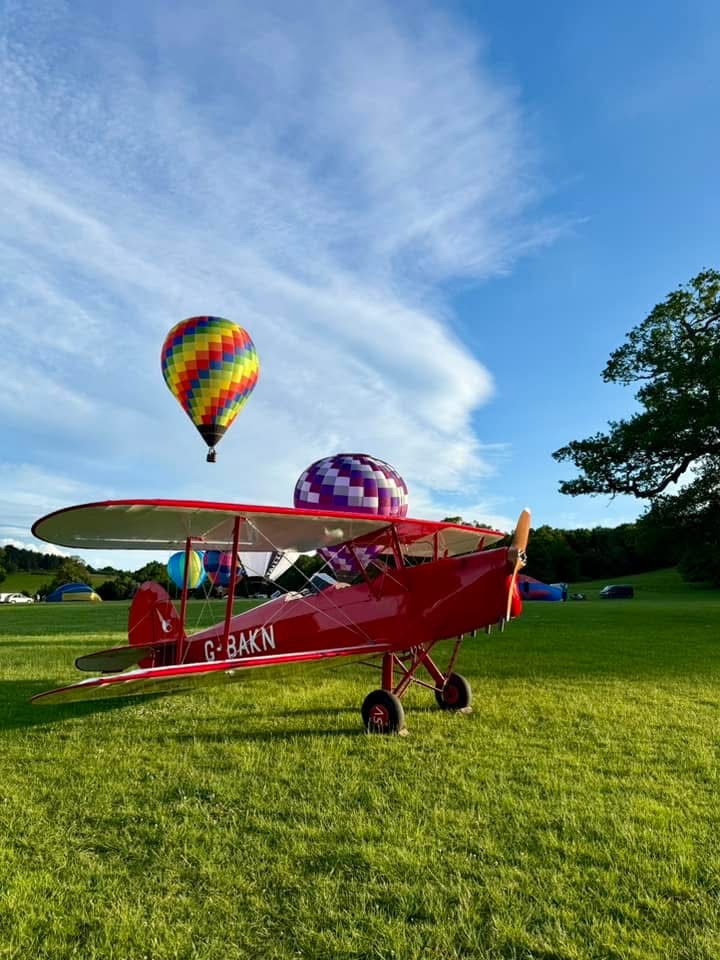 Hot air balloons behind stationary aeroplane.